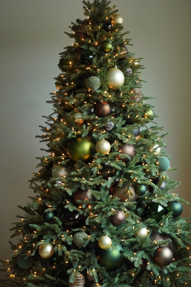 Interior holiday tree styled with olive, gold, and bronze ornaments and warm lights
